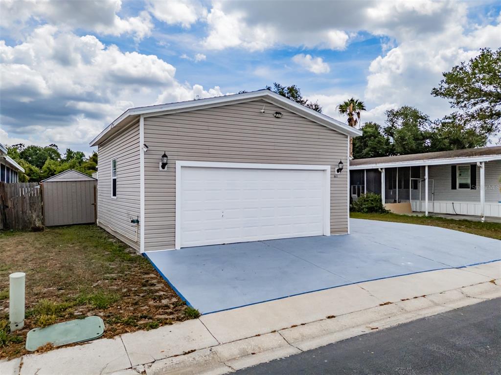 A detached garage with light-colored siding and a white door sits beside a driveway — 8471 FANTASIA PARK WAY, RIVERVIEW, FL