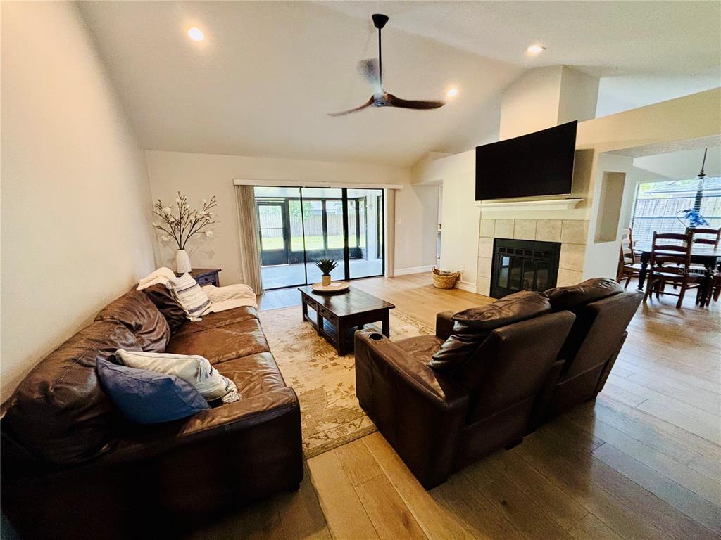 A living room features a brown leather sofa, matching recliners, a fireplace, and sliding glass doors — 1045 SHAFFER TRAIL, OVIEDO, FL