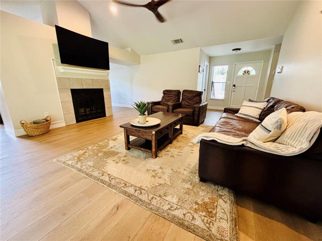 A living room features a fireplace, a brown leather sofa, and light wood flooring — 1045 SHAFFER TRAIL, OVIEDO, FL