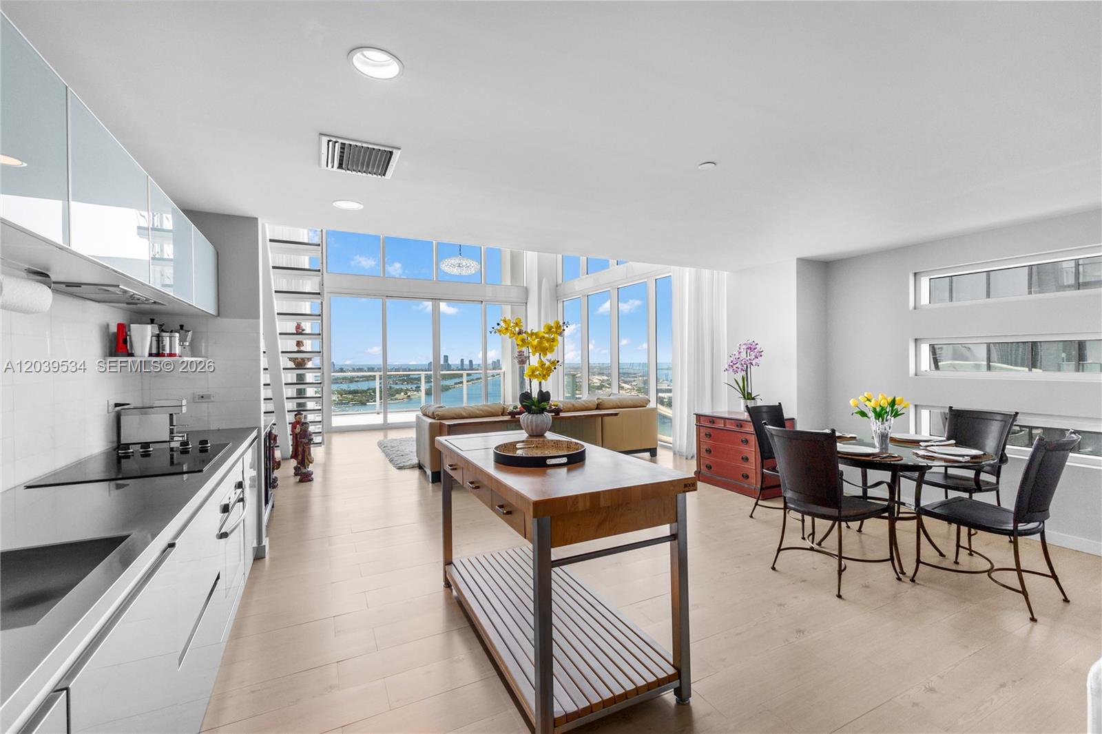 A modern open-plan kitchen, dining area, and living room feature floor-to-ceiling windows with water views — 1040 Biscayne Blvd # 3101, Miami FL 33132, MIAMI, FL