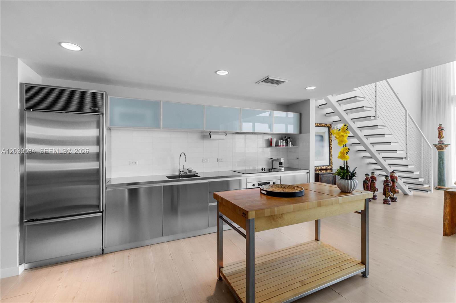 A modern kitchen features stainless steel cabinets, a wooden island, and an open staircase — 1040 Biscayne Blvd # 3101, Miami FL 33132, MIAMI, FL