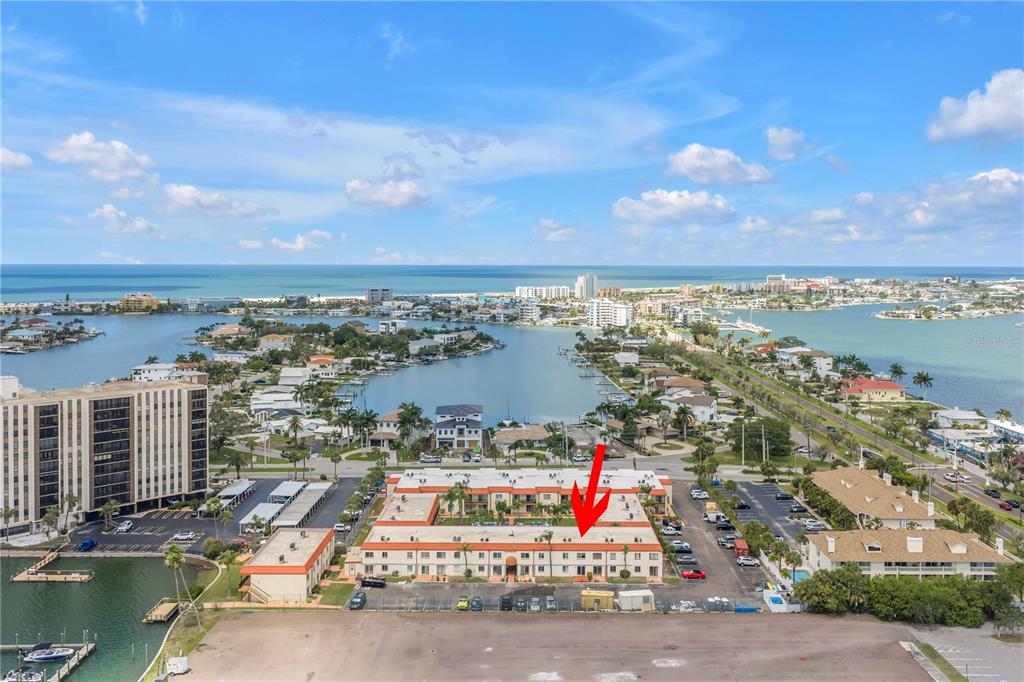 An aerial view shows a multi-story apartment complex with a red arrow pointing to the roof — 10375 PARADISE BOULEVARD UNIT 51, TREASURE ISLAND, FL