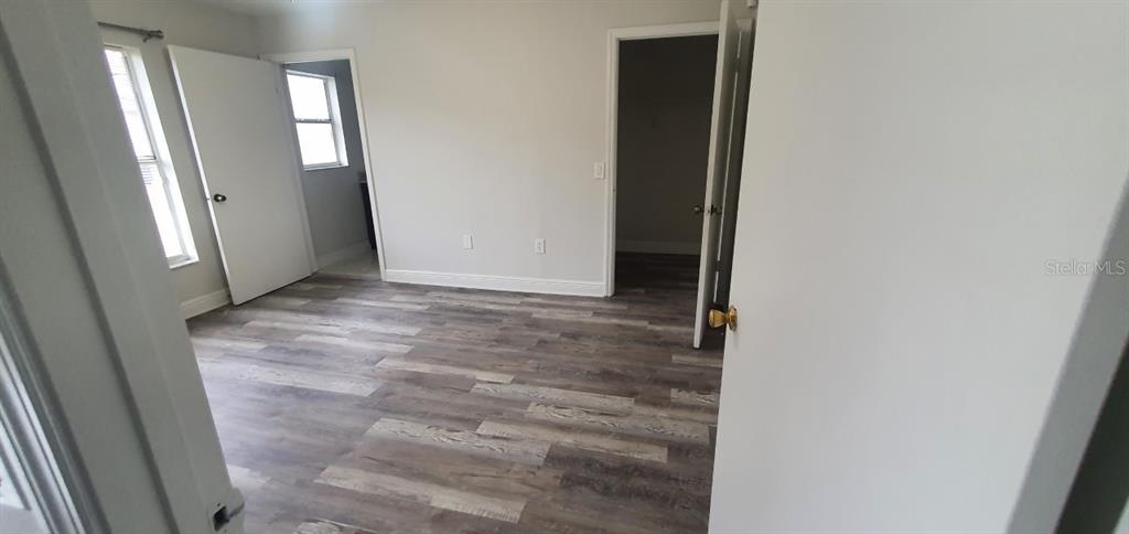 An empty bedroom features light gray walls, wood-look vinyl flooring, and two open doorways — 1215 BAREFOOT BAY DRIVE, ORLANDO, FL