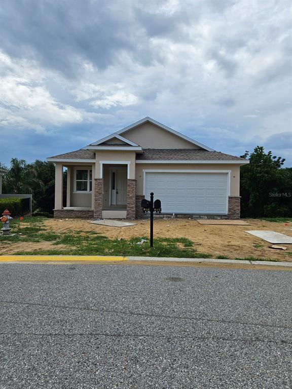 A single-story house with a white garage door, stone accents, and an unfinished dirt yard — 537 PINELOCH DRIVE, HAINES CITY, FL