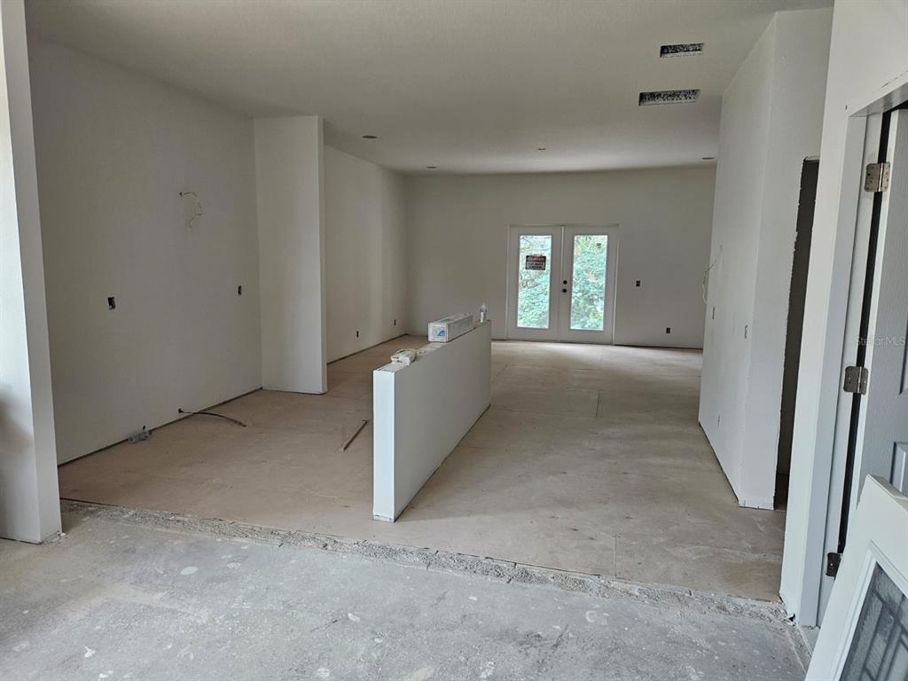 An unfinished room with white walls, a partial partition wall, and glass double doors — 537 PINELOCH DRIVE, HAINES CITY, FL