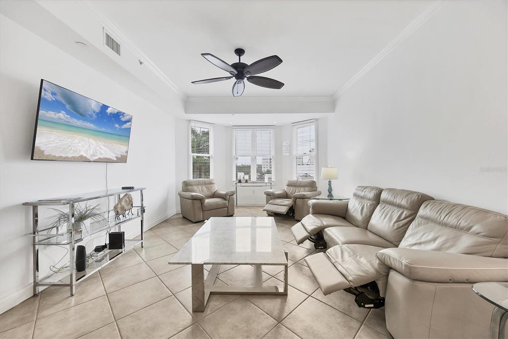 A living room features light tile floors, a ceiling fan, and a leather reclining sofa set — 8111 LAKEWOOD MAIN STREET UNIT 304, LAKEWOOD RANCH, FL