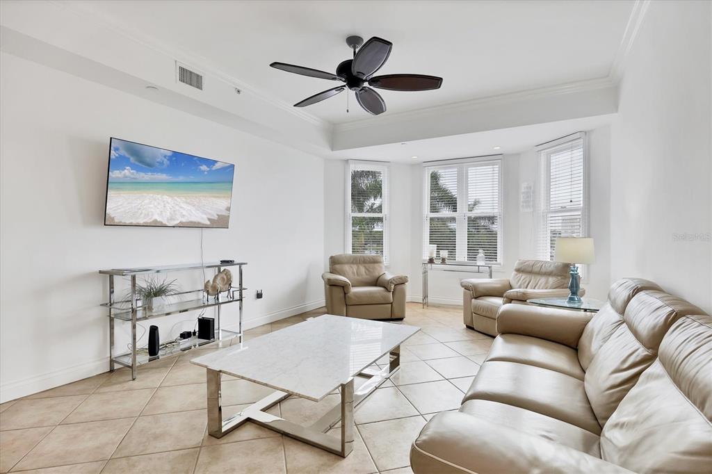 A living room features a marble coffee table, leather seating, and a wall-mounted television — 8111 LAKEWOOD MAIN STREET UNIT 304, LAKEWOOD RANCH, FL