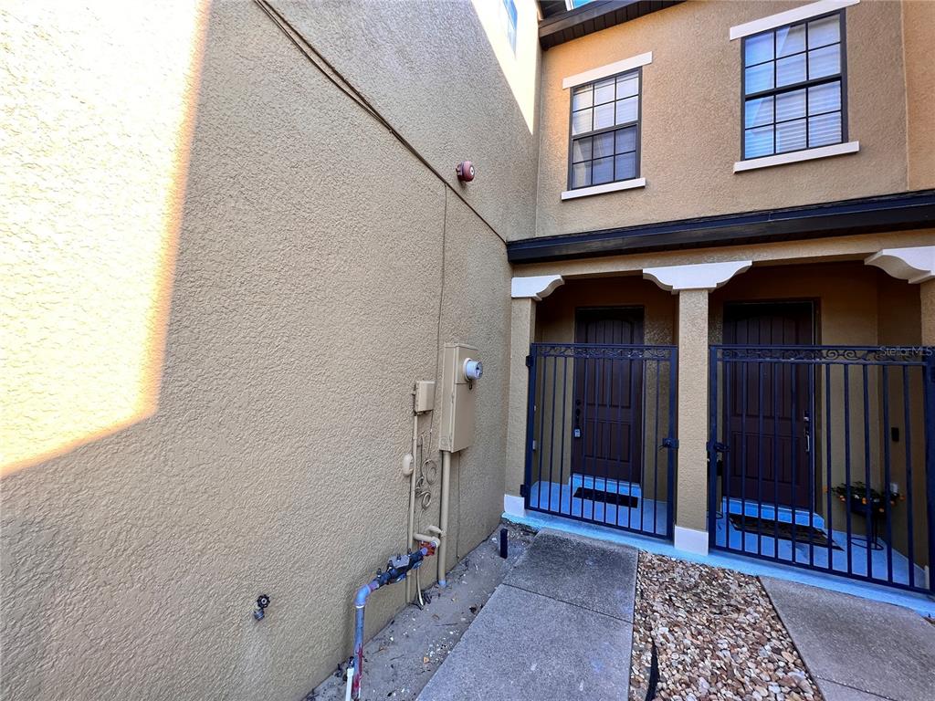 An exterior view shows a stucco wall with utility equipment and two gated entryways — 2342 ALOHA BAY COURT, OCOEE, FL