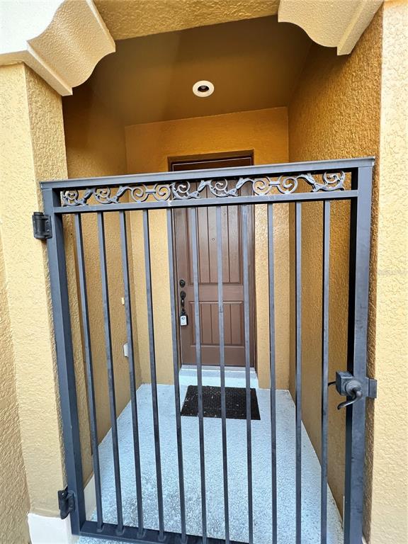 A metal gate stands in front of a recessed entryway with a brown front door — 2342 ALOHA BAY COURT, OCOEE, FL