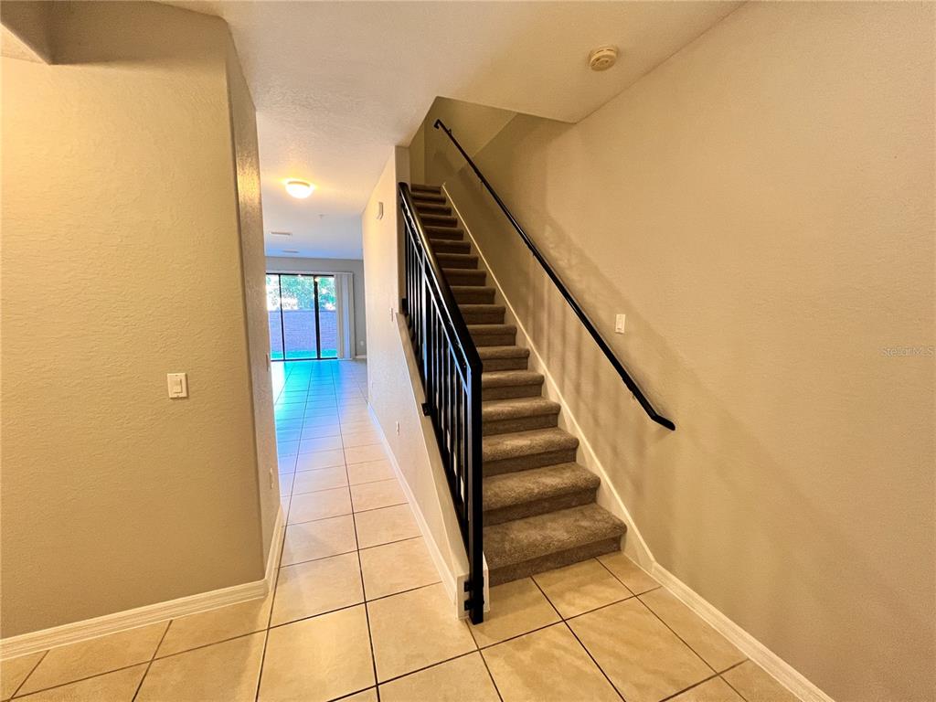 An interior view shows a carpeted staircase with a black railing beside a tiled hallway — 2342 ALOHA BAY COURT, OCOEE, FL