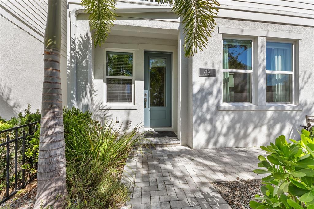 The exterior of a home features a blue front door, a paved walkway, and landscaping — 2467 MANGUM COURT, SARASOTA, FL