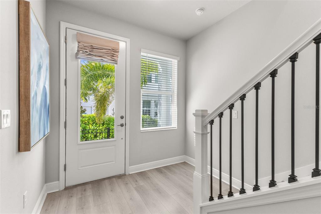 An entryway with light wood flooring, a white front door, a window, and a staircase — 2467 MANGUM COURT, SARASOTA, FL