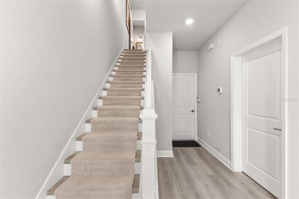 A carpeted staircase with a white railing leads upward in a hallway with light flooring — 2467 MANGUM COURT, SARASOTA, FL