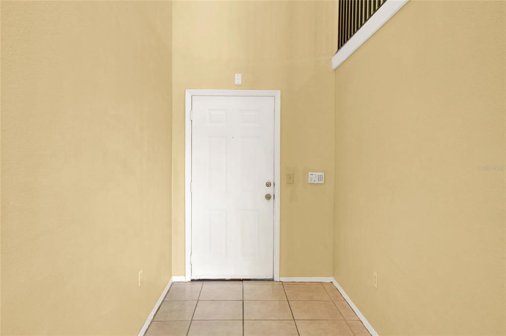 A living room with beige tile floors, a spiral staircase, and sliding glass balcony doors — 1325 ROTONDA POINT UNIT 337, LAKE MARY, FL