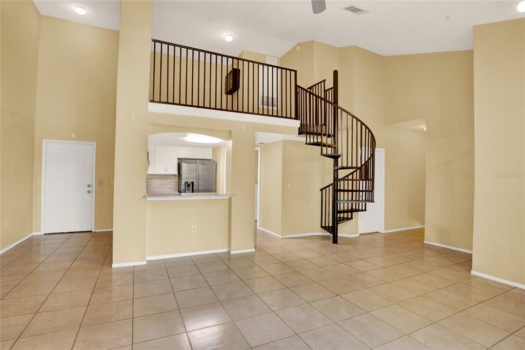 A living room with tile floors, a spiral staircase, and a loft overlooking the kitchen — 1325 ROTONDA POINT UNIT 337, LAKE MARY, FL