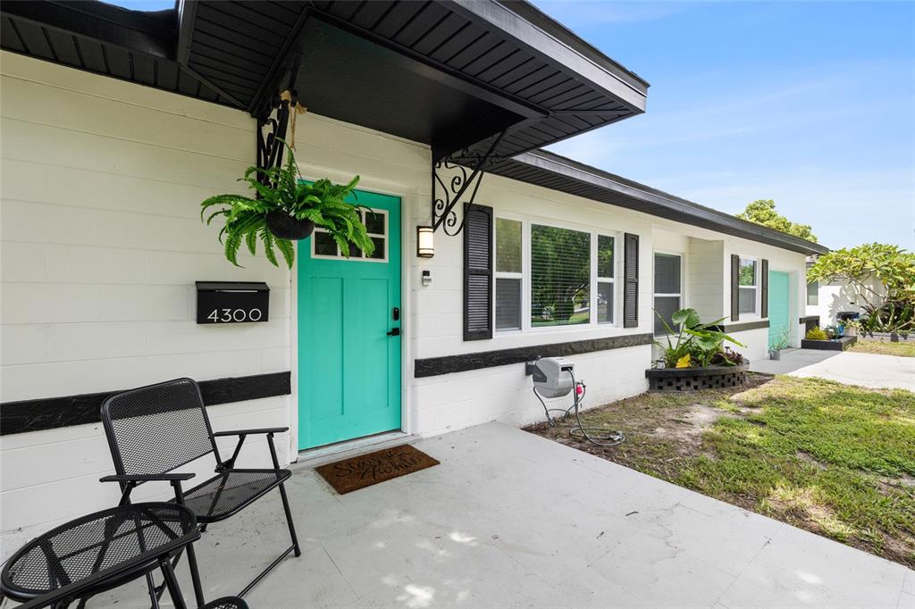 A white house exterior features a bright teal front door, black shutters, and a porch — 4300 28TH AVENUE N, ST PETERSBURG, FL