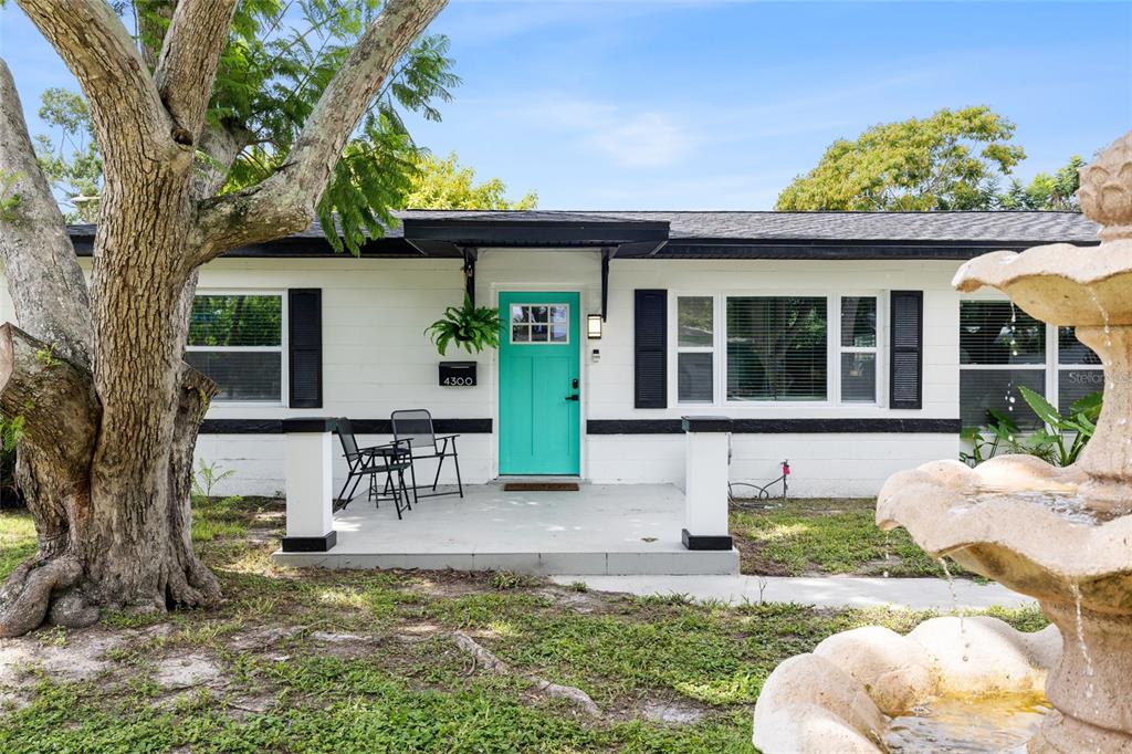 A white house with black shutters, a turquoise front door, and a stone fountain — 4300 28TH AVENUE N, ST PETERSBURG, FL