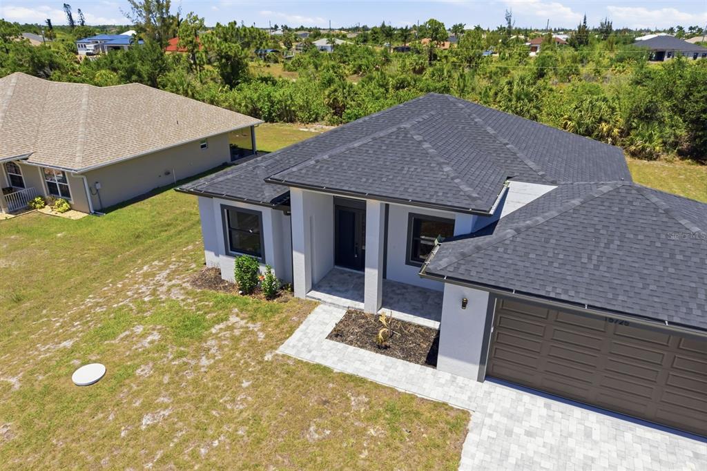 An aerial view of a single-story house with a dark shingled roof and paved driveway — 15725 AUTRY CIRCLE, PORT CHARLOTTE, FL