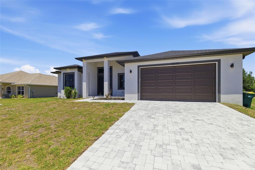 A single-story house with a paved driveway, a two-car garage, and a covered entryway — 15725 AUTRY CIRCLE, PORT CHARLOTTE, FL
