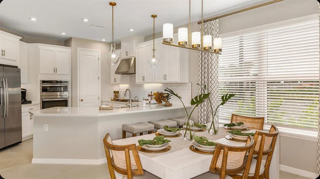 A kitchen with white cabinets and a dining area featuring a wooden table and chairs — 11743 SOFT MEADOW MEWS, SAN ANTONIO, FL