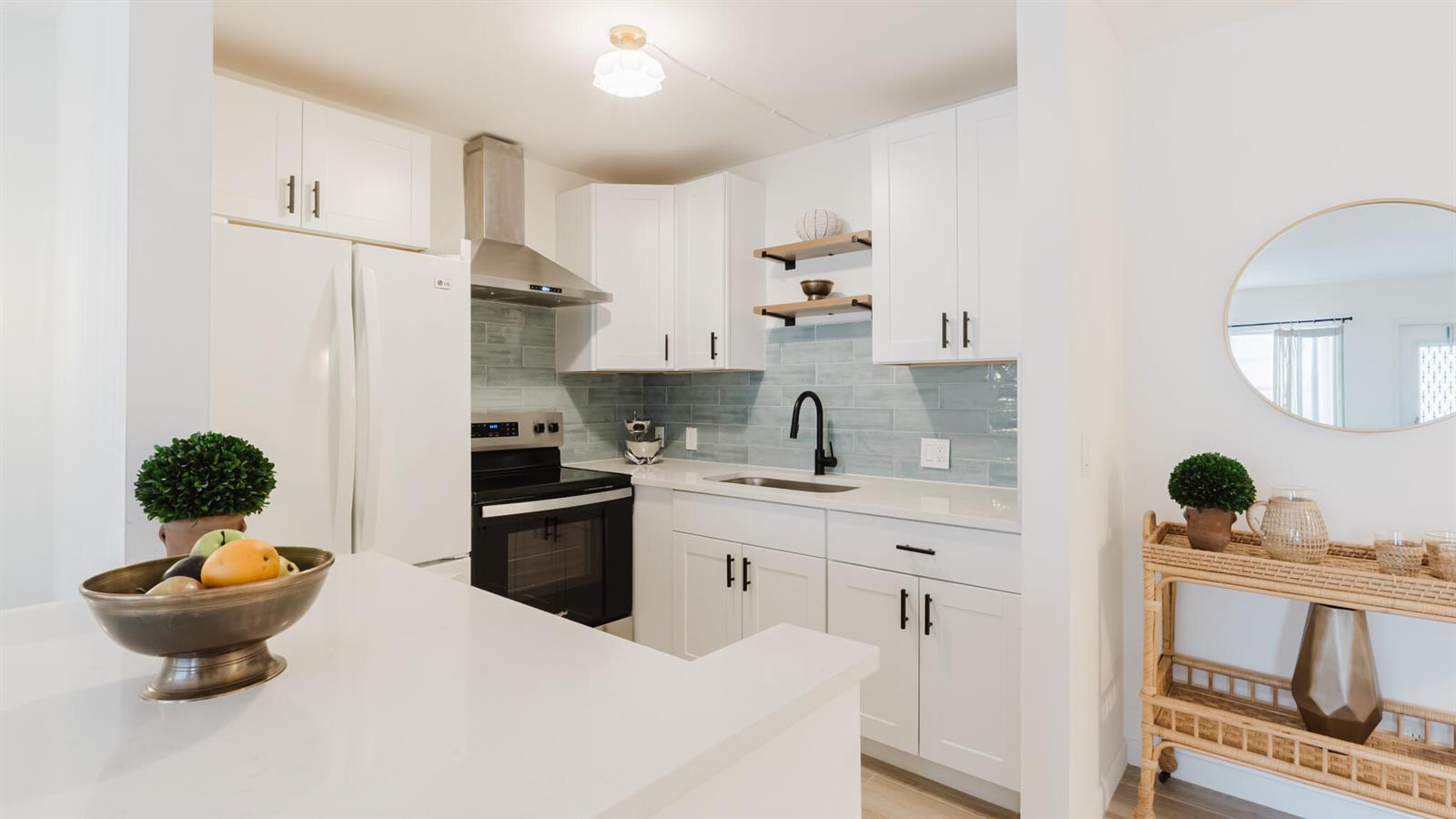 A white kitchen features light blue subway tile backsplash, stainless appliances, and wooden floating shelves — 272 Preston G Way, Boca Raton FL 33434, BOCA RATON, FL