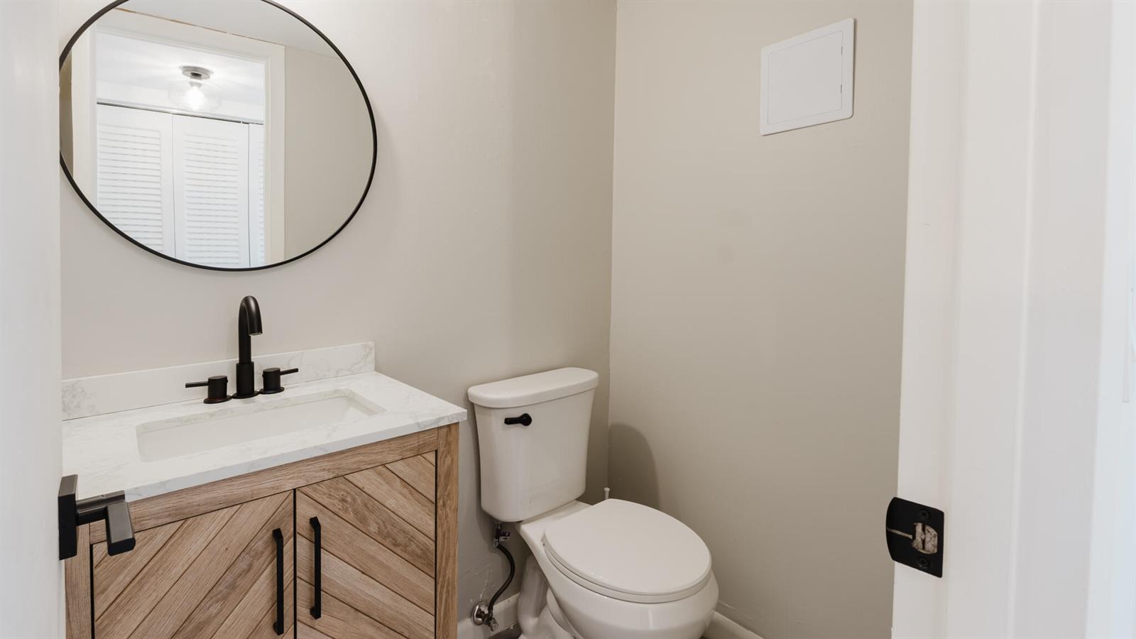 A bathroom features a wood vanity with a white countertop, a round mirror, and toilet — 272 Preston G Way, Boca Raton FL 33434, BOCA RATON, FL