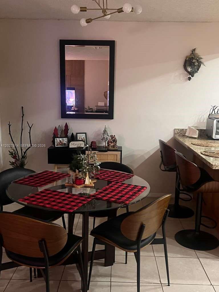 A dining area features a glass-topped table with red plaid placemats and modern chairs — 3473 SW 52nd Ave, Pembroke Pines FL 33023, PEMBROKE PINES, FL