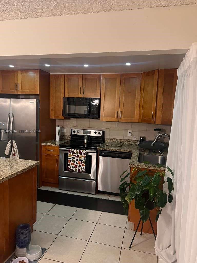 A kitchen features wood cabinets, stainless steel appliances, granite countertops, and light-colored tile flooring — 3473 SW 52nd Ave, Pembroke Pines FL 33023, PEMBROKE PINES, FL