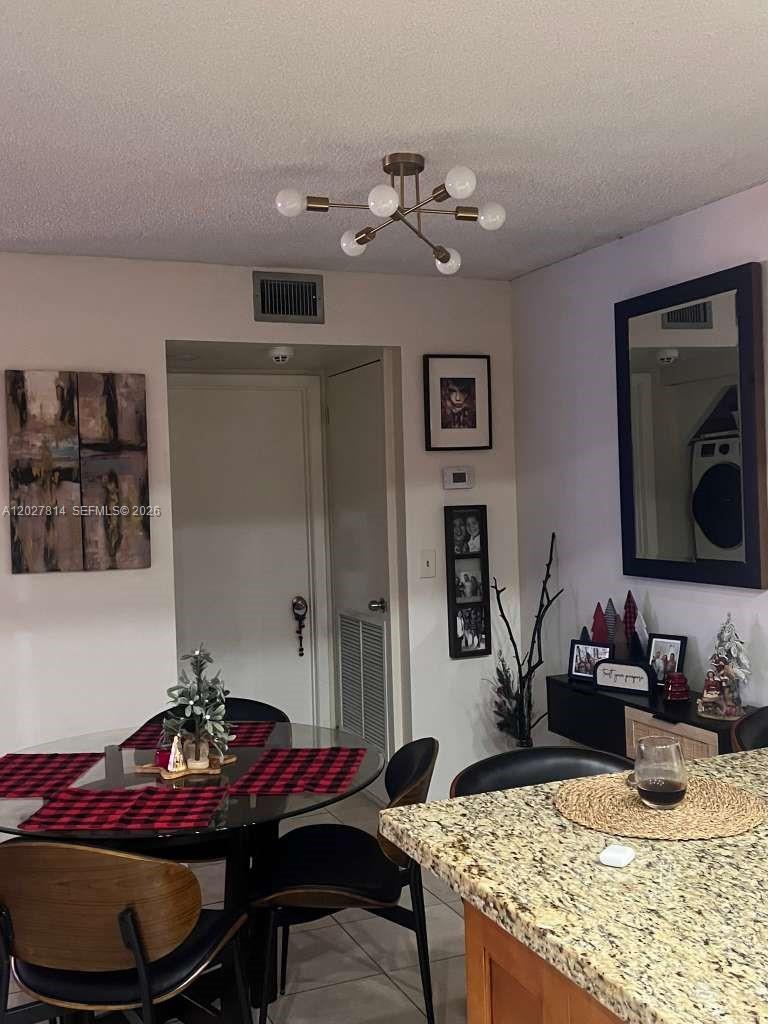 A dining area features a glass table, modern chandelier, and a granite-topped kitchen island — 3473 SW 52nd Ave, Pembroke Pines FL 33023, PEMBROKE PINES, FL