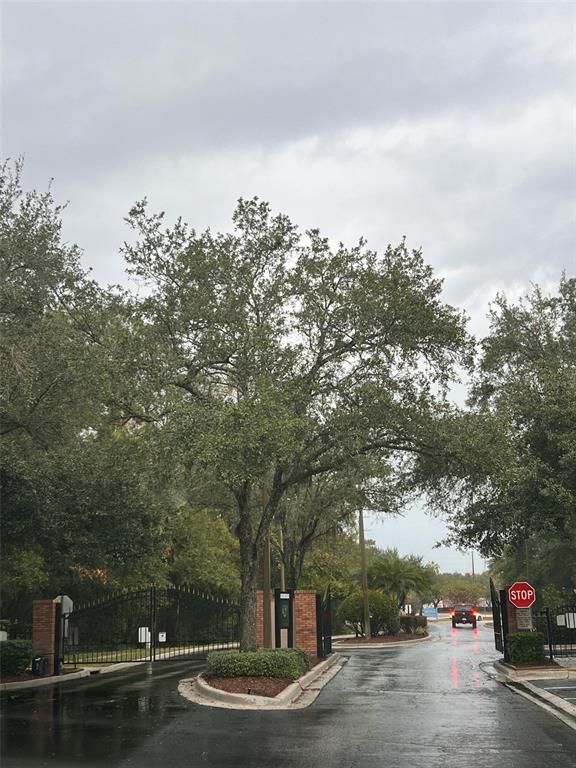 A gated entrance with a brick pillar, a large tree, and a stop sign — 8674 HUNTERS KEY CIRCLE, TAMPA, FL