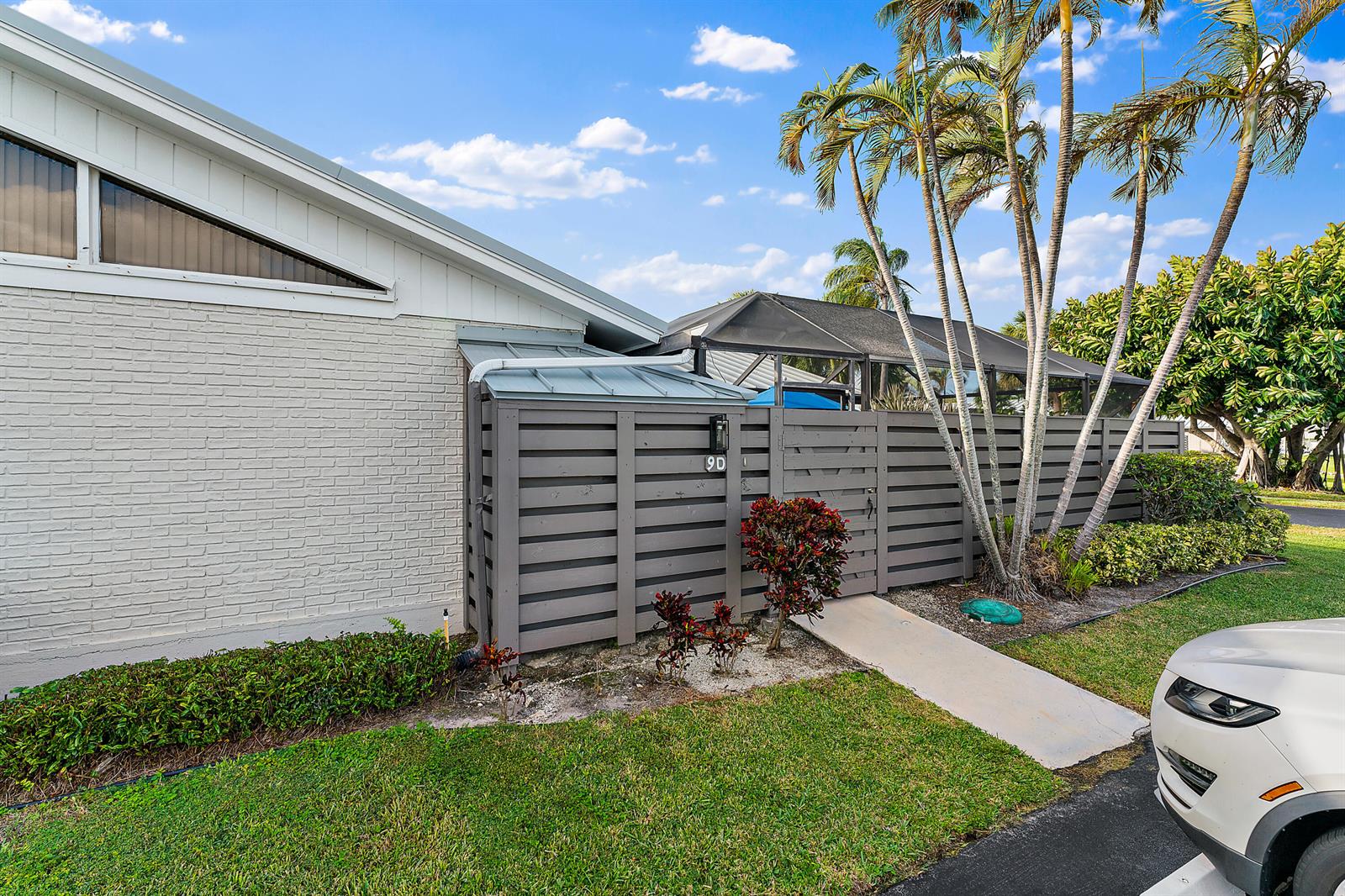 A gray horizontal slat fence encloses a patio area next to a white brick building — 1801 S Us Highway 1 # 9d, Jupiter FL 33477, JUPITER, FL