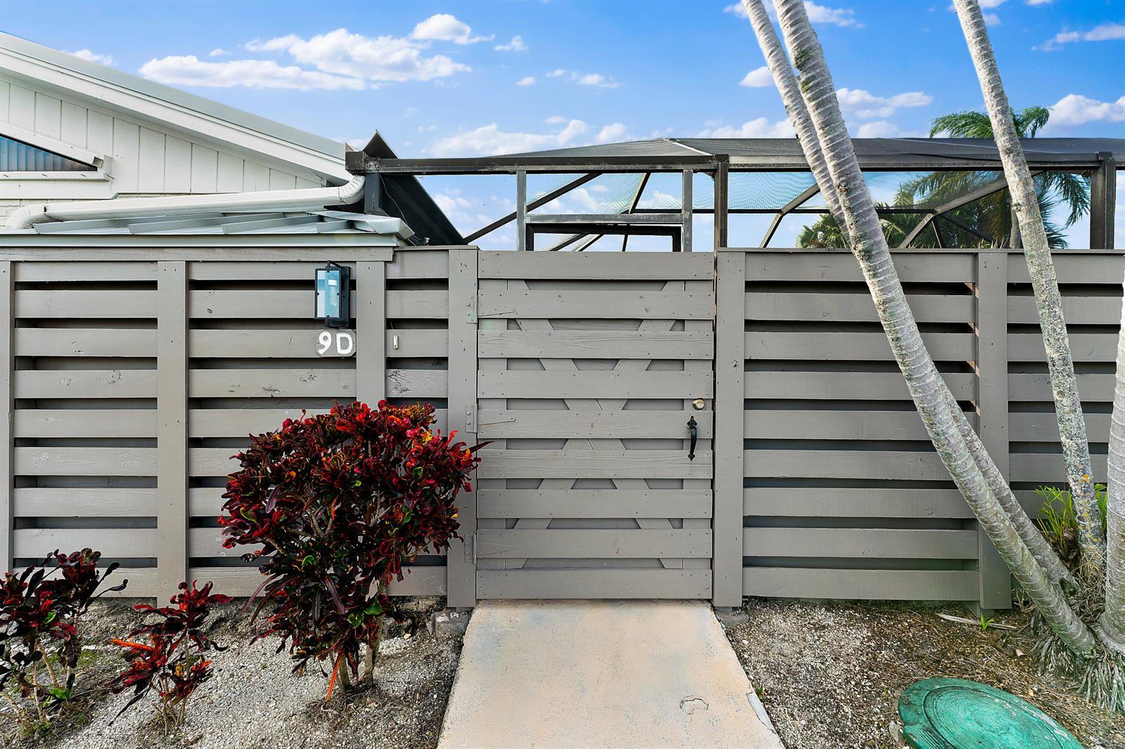 A gray wooden fence with a gate and house number 9D stands before a screened enclosure — 1801 S Us Highway 1 # 9d, Jupiter FL 33477, JUPITER, FL