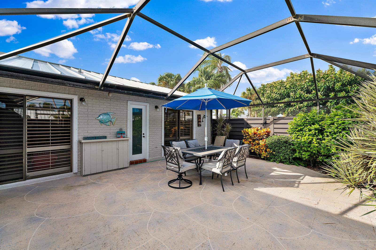 A screened-in patio features a dining set under a blue umbrella on a concrete floor — 1801 S Us Highway 1 # 9d, Jupiter FL 33477, JUPITER, FL