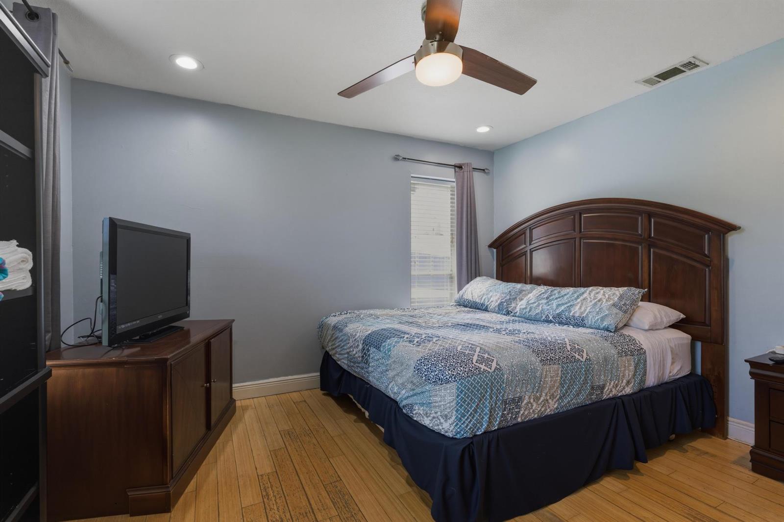 A bedroom features light blue walls, a dark wood bed frame, and hardwood flooring — 224 NW 9th Street, Pompano Beach FL 33060, POMPANO BEACH, FL