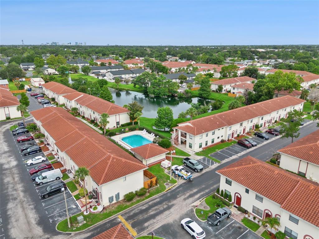 An aerial view shows multi-story apartment buildings with red tile roofs surrounding a central pond — 6297 RIVER RUN PLACE UNIT 197, ORLANDO, FL