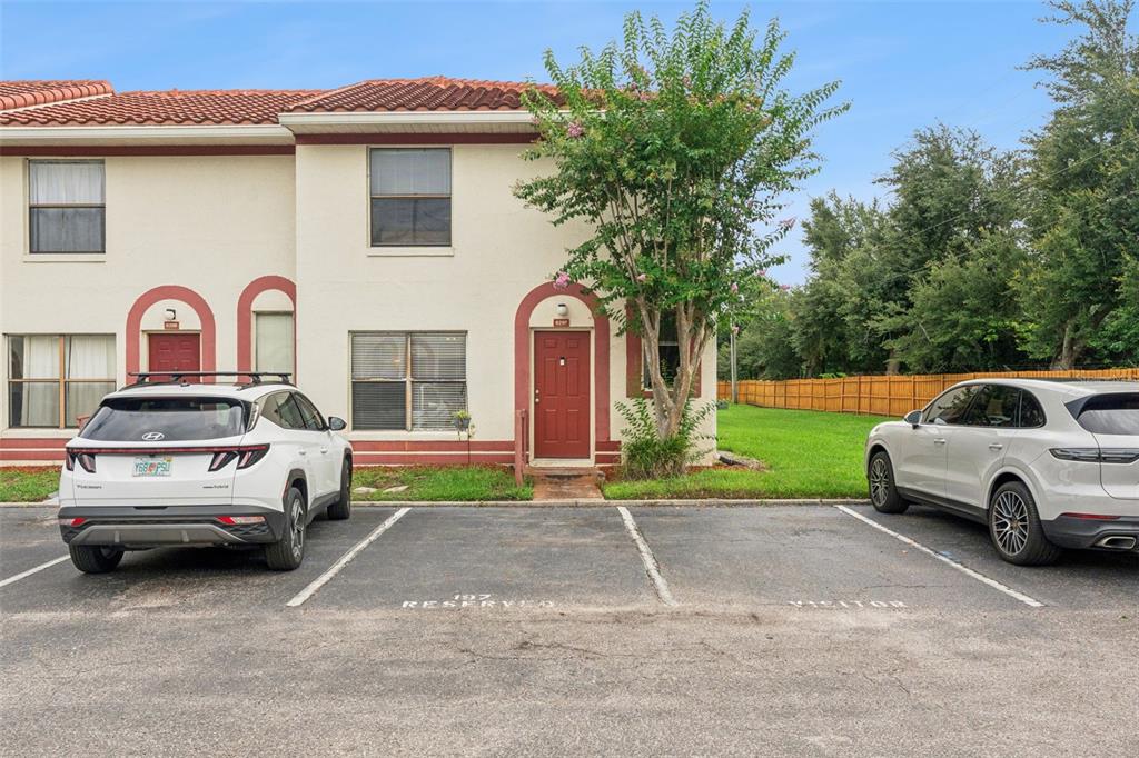 A two-story townhouse exterior with a red door, tiled roof, and two parked cars — 6297 RIVER RUN PLACE UNIT 197, ORLANDO, FL