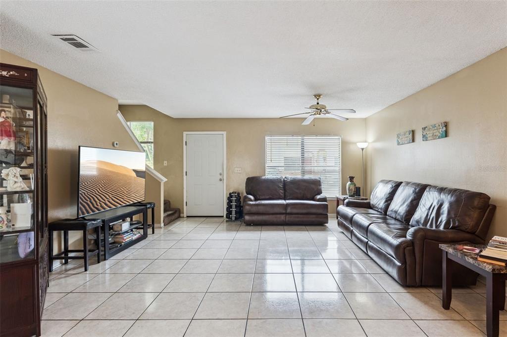 A living room with tile flooring, a brown leather sofa set, and a television — 6297 RIVER RUN PLACE UNIT 197, ORLANDO, FL