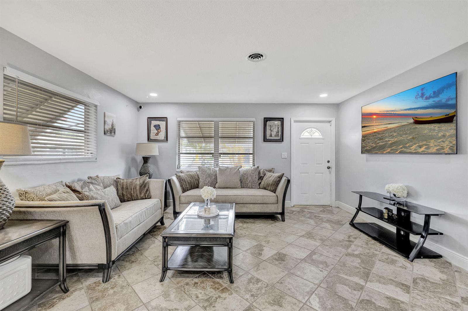 A living room features two beige sofas, a glass-top coffee table, and tile flooring — 4901 NW 27th Way, Tamarac FL 33309, TAMARAC, FL