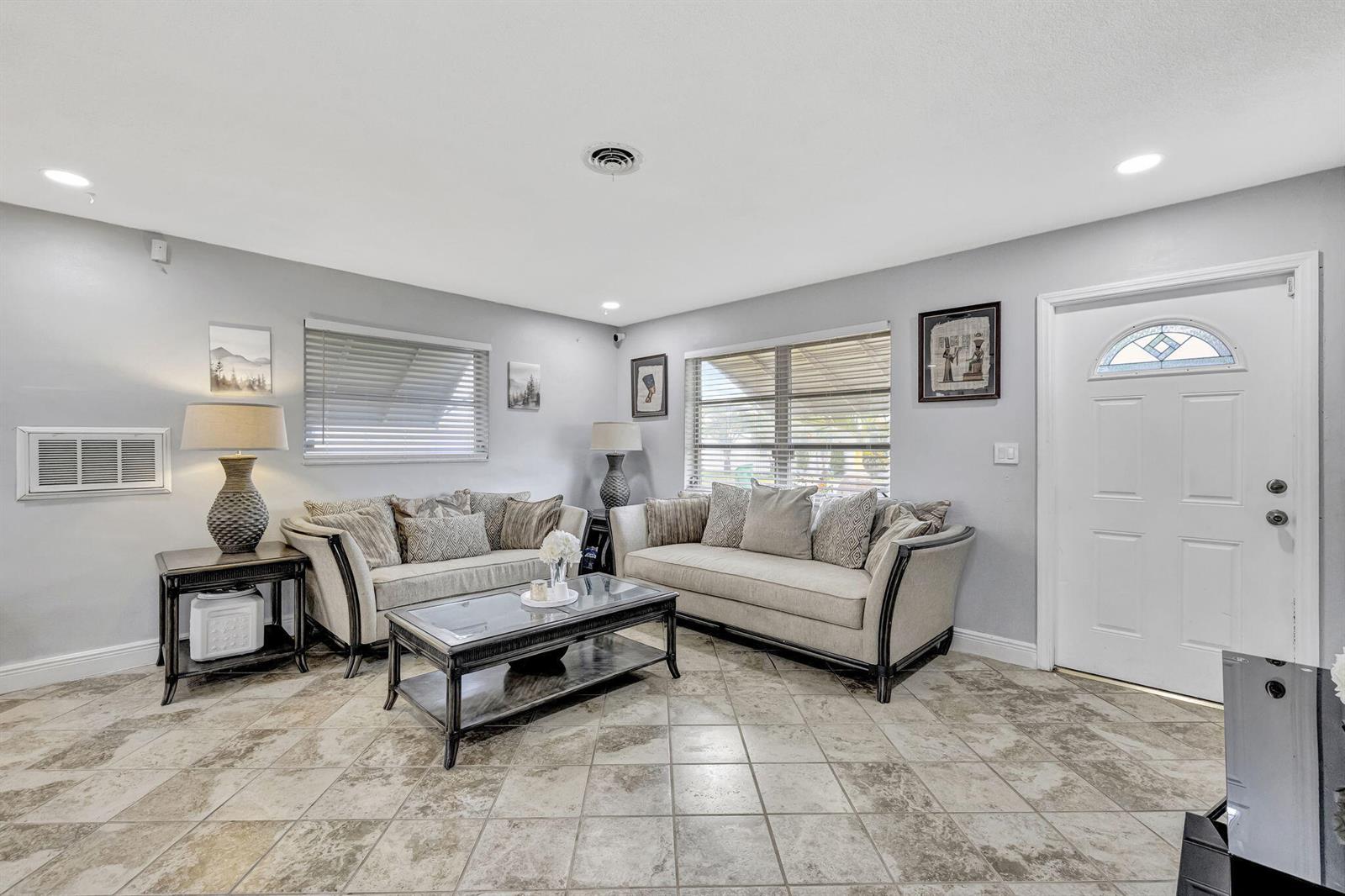 A living room features light gray walls, tile flooring, two sofas, and a glass coffee table — 4901 NW 27th Way, Tamarac FL 33309, TAMARAC, FL