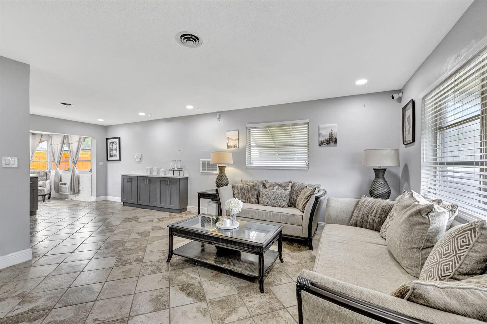 A living room features tile flooring, two beige sofas, a glass coffee table, and cabinetry — 4901 NW 27th Way, Tamarac FL 33309, TAMARAC, FL