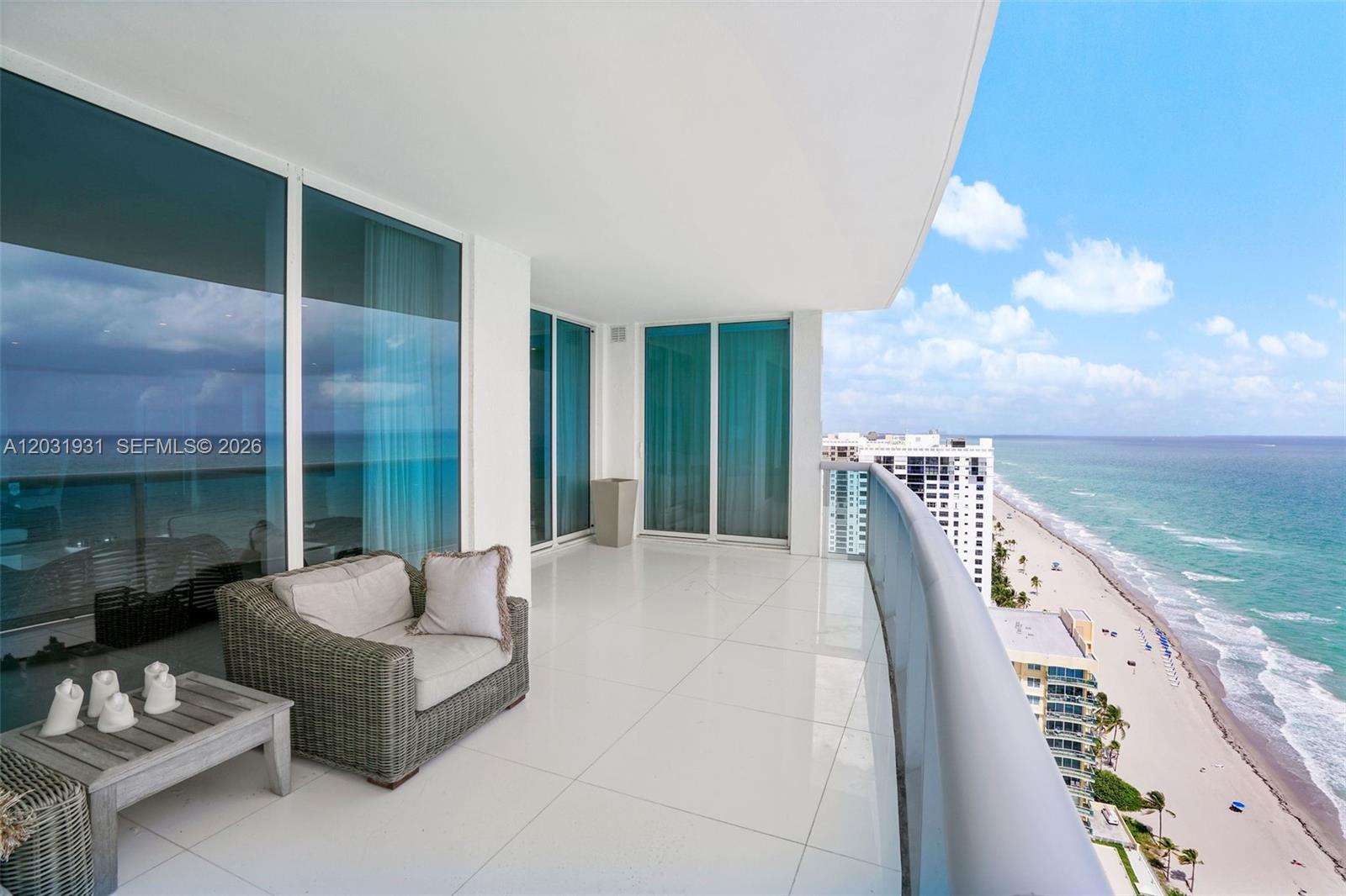 A high-rise balcony features white tile flooring, a wicker chair, and oceanfront beach views — 2711 S Ocean Dr # 2803, Hollywood FL 33019, HOLLYWOOD, FL