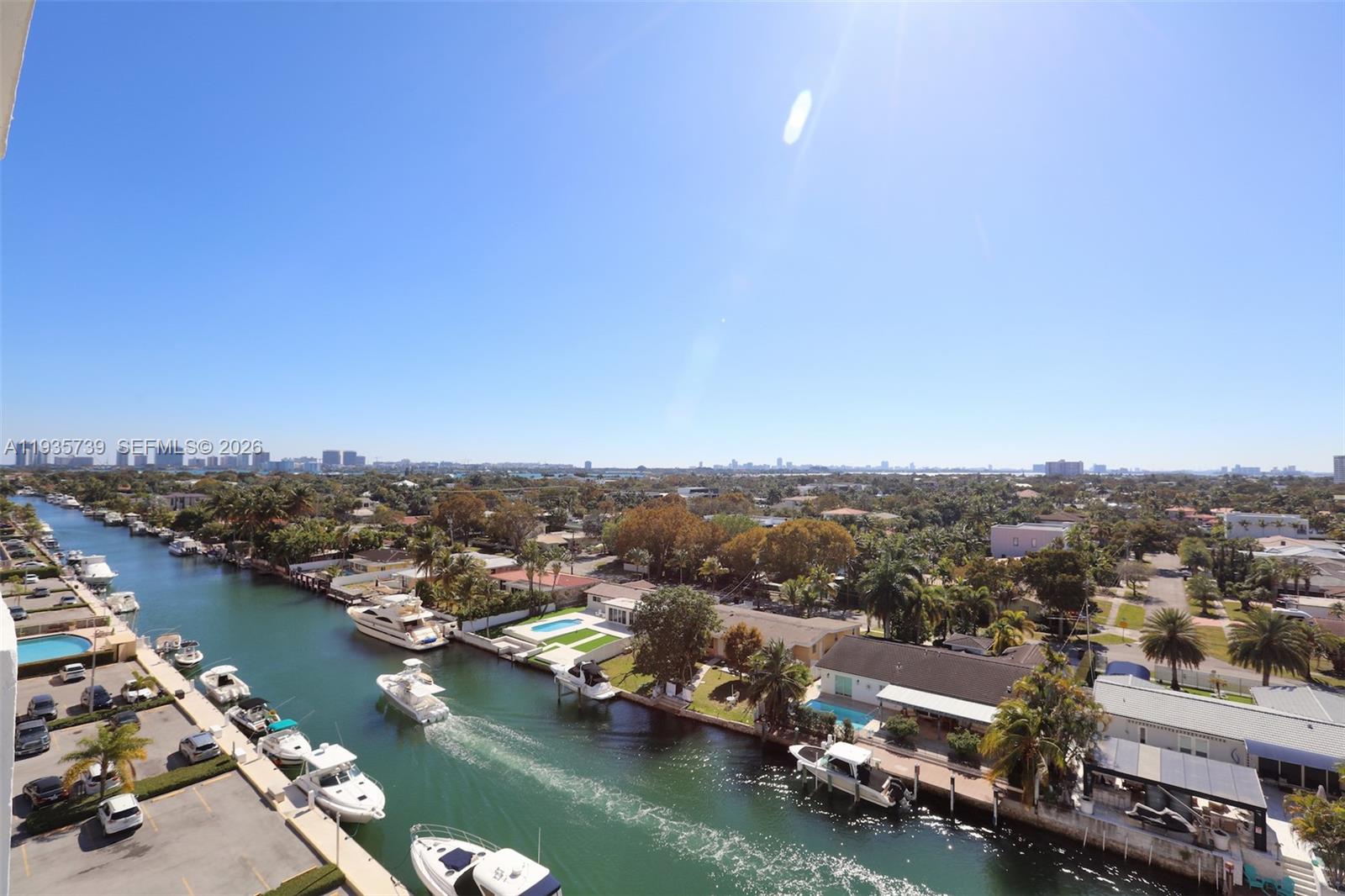 An aerial view shows a canal with docked boats and residential homes under a clear sky — 2000 NE 135th St # 908, North Miami FL 33181, NORTH MIAMI, FL
