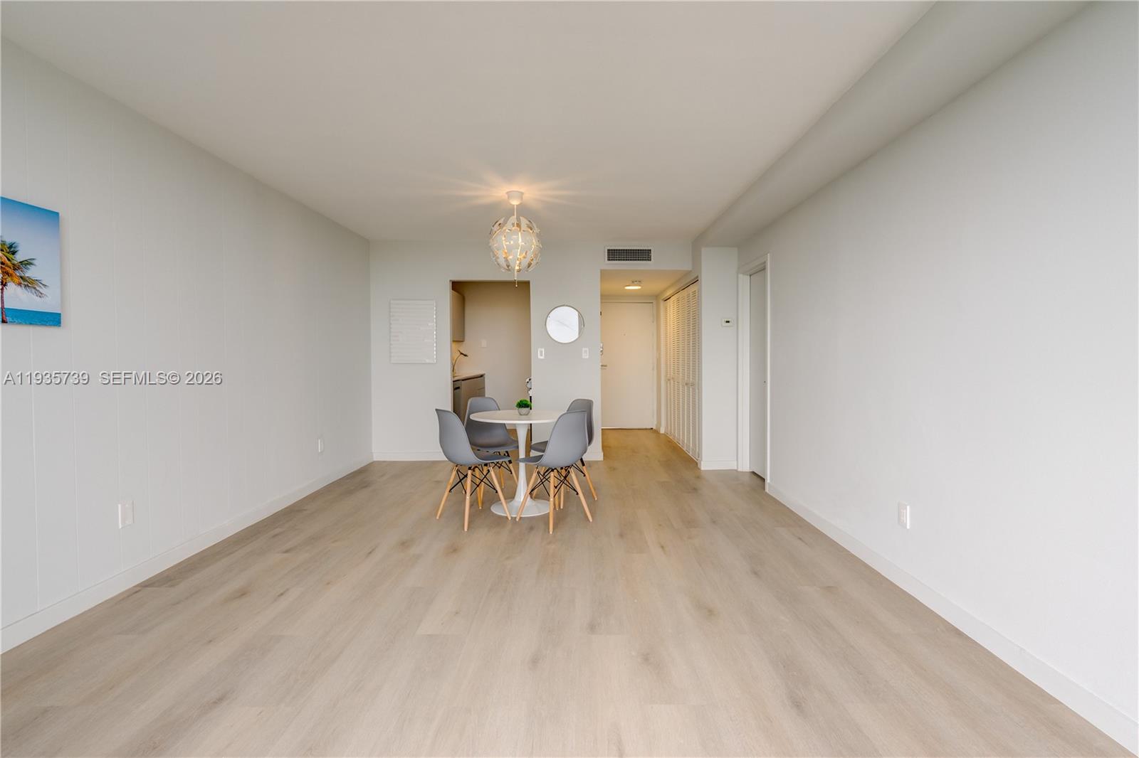 A dining area features a round white table with four grey chairs on light wood flooring — 2000 NE 135th St # 908, North Miami FL 33181, NORTH MIAMI, FL