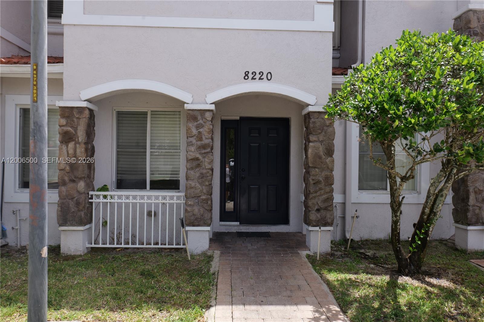 The exterior of a two-story residential building features a stone-accented entryway and a paved walkway — 8220 SW 25th Ct # 106, Miramar FL 33025, MIRAMAR, FL