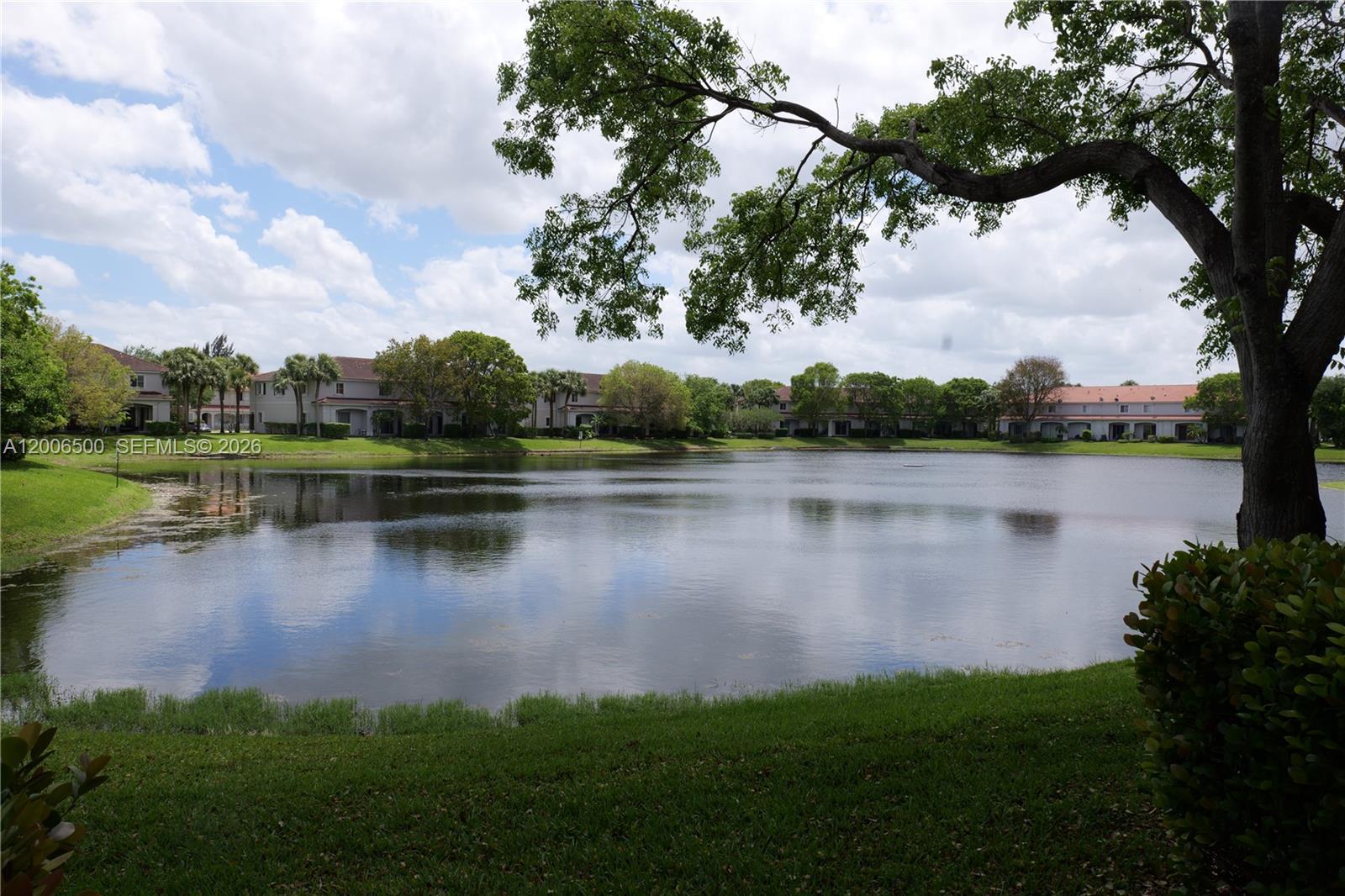 A view of a calm lake surrounded by residential buildings and lush green trees — 8220 SW 25th Ct # 106, Miramar FL 33025, MIRAMAR, FL