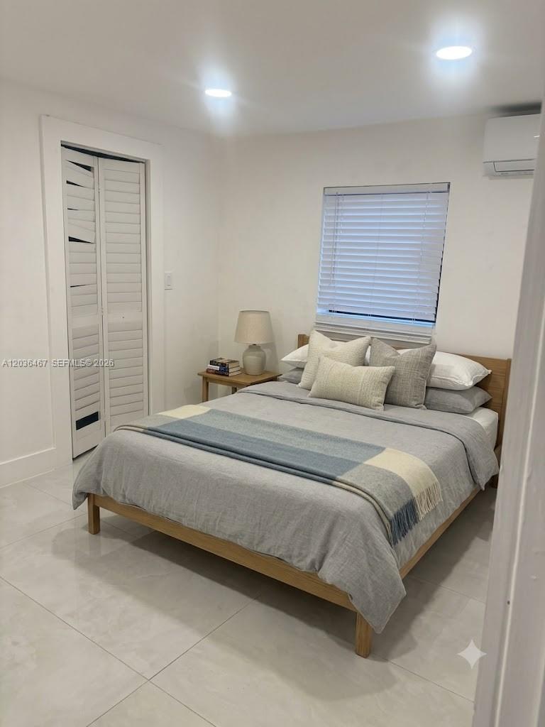 A bedroom features a wooden bed frame, white walls, tile flooring, and a closet — 1321 NE 212th Ter # 2, Miami FL 33179, MIAMI, FL