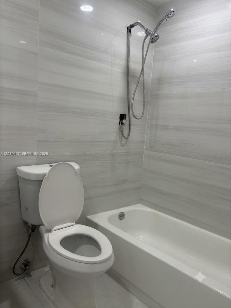 A bathroom features a white toilet, a bathtub, and a handheld shower head — 1321 NE 212th Ter # 2, Miami FL 33179, MIAMI, FL