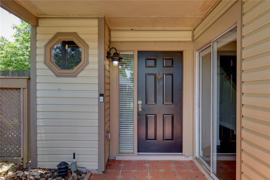 A front entryway features a dark door, a side window, and a tiled porch — 904 NORFOLK COURT, LONGWOOD, FL