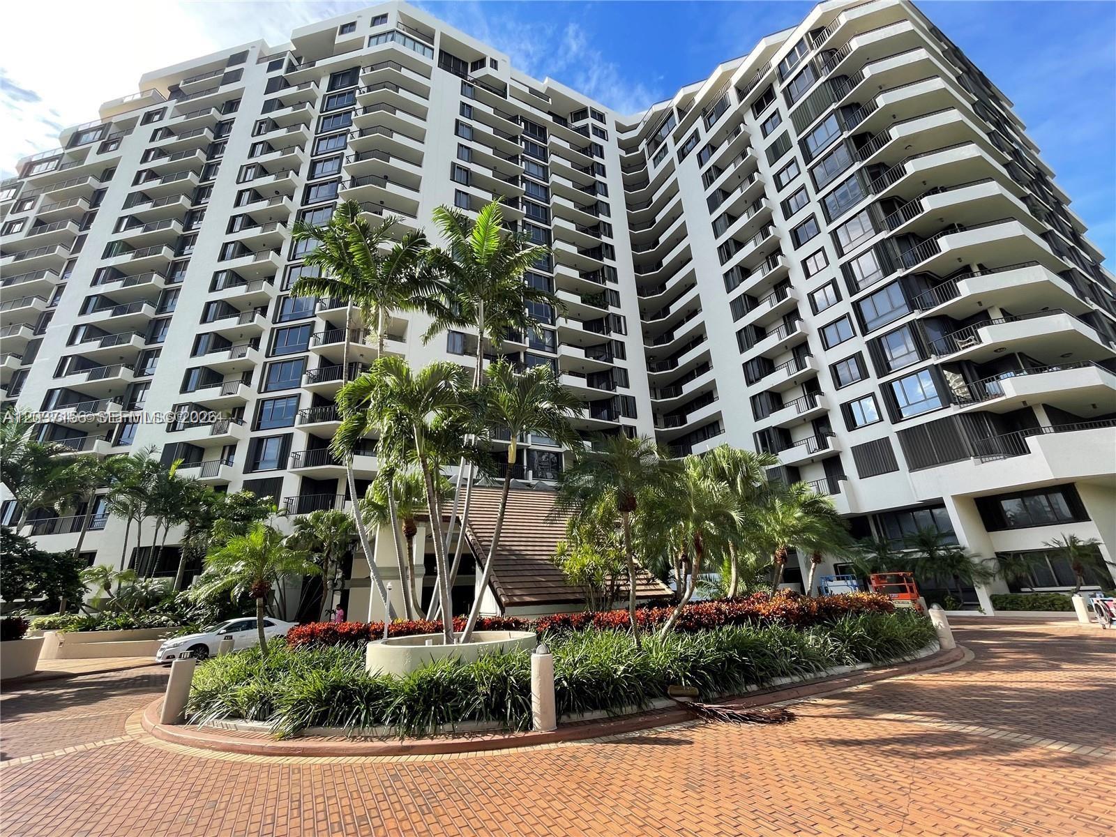 A multi-story residential building features balconies and a landscaped circular driveway with palm trees — 520 Brickell Key Dr # A1005, Miami FL 33131, MIAMI, FL