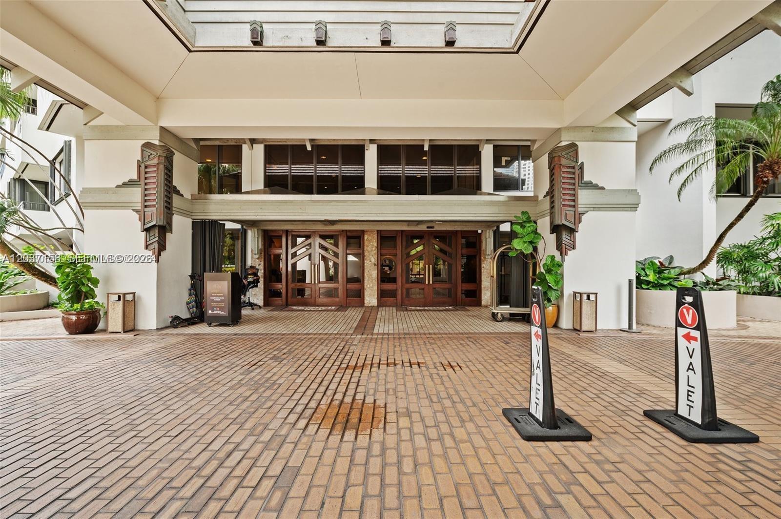 The exterior entrance of a building features a brick driveway, valet signs, and wooden doors — 520 Brickell Key Dr # A1005, Miami FL 33131, MIAMI, FL